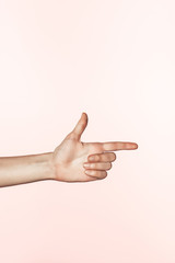 cropped image of woman pointing by finger isolated on pink background