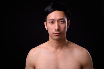 Fototapeta premium Young handsome Asian man shirtless against black background