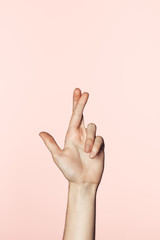 Fototapeta premium cropped image of woman doing crossed fingers gesture isolated on pink background