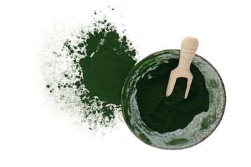 Spirulina powder in a ceramic green cup with a wooden scoop isolated on a white background.Super food