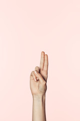 cropped image of woman doing two raised fingers gesture isolated on pink background