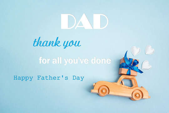 Father's Day greeting message with wooden toy car with a gift box on the roof on blue background