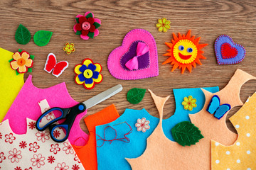 Crafts made of felt in the form of heart, sun and butterflies. Motley colorful felt for art and handicrafts. Felt and crafts on a wooden background. View from above.