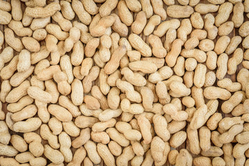 Peanuts in shell, glass bowl of peanut butter on wooden background with copy space. Flatlay. Heathy food.