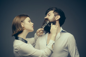Barbershop or hairdresser concept. Woman hairdresser cuts beard with scissors. Man with long beard, mustache and stylish hair, grey background. Guy with modern hairstyle visiting hairdresser.