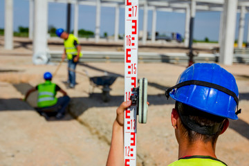 Worker is holding leveling rod to measuring level on construction site
