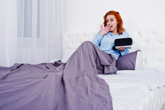 Red haired girl in bed with vr glasses at studio room.