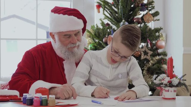 Little boy draw picture with Santa Claus