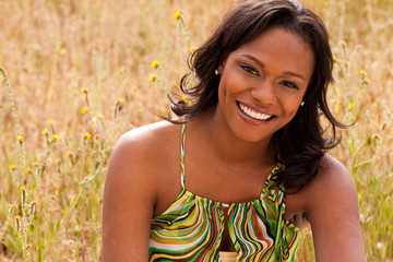 Happy woman sitting in a field smiling.