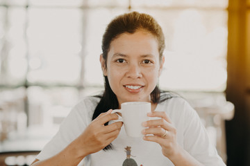  Asian girl is sitting to drink coffee at a coffee shop