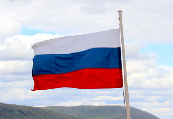 Flag of the Russian Federation streaming in the wind against the cloudy sky