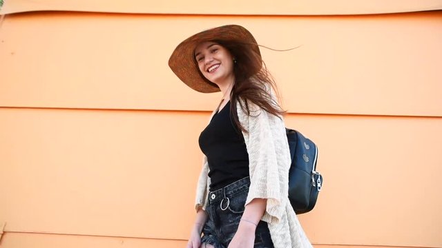 Young attractive stylish woman wearing straw hat poiting at camera and calling to follow her on yellow background. Travel concept.