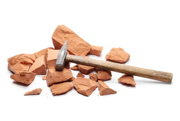 Shattered brick pieces and hammer isolated on white background