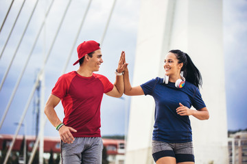 Happy couple running across the bridge. Healthy lifestyle.