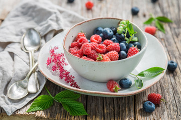 Sweet blueberries and raspberries in white bowl
