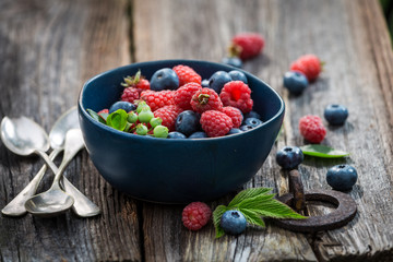Juicy blueberries and raspberries in blue dark bowl