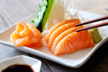 Sashimi, Salmon, Japanese food chopsticks and wasabi on the wood table
