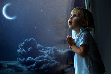 the child looks out the window into the night sky