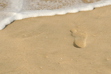 Footprint before getting washed away on a beach indicating disruption