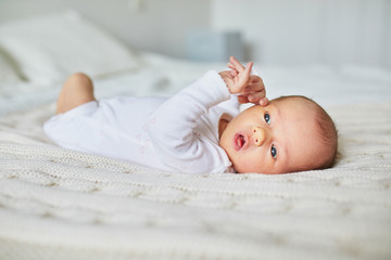 Baby girl lying on bed in nursery