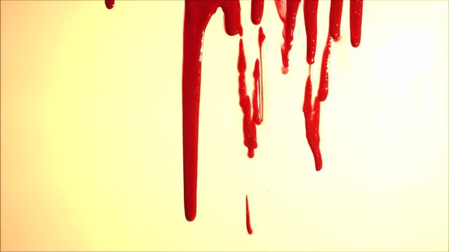 Blood splatter. Blood dripping down over light background. Red liquid.