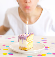 Mujer soplando una vela en un trozo de pastel de cumpleaños sobre fondo blanco