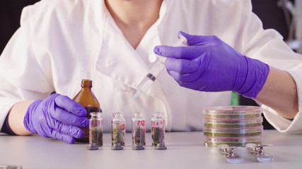 Close up. The scientist's hands pouring solvent into the bottles with samples