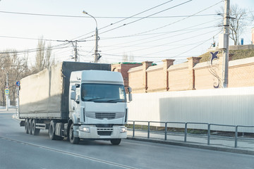 Big white truck passes through city street