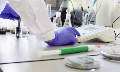 Close up hands of a scientist in the laboratory setting up an electronic pH meter