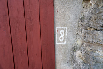 An eight painted next to a red door. Next to a medieval wall.