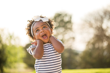 Happy little girl laughing and smiling outside. - obrazy, fototapety, plakaty
