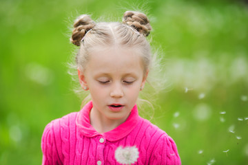 Beautiful little girl blowing dandelion