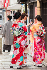 KYOTO, JAPAN - NOVEMBER 7, 2017: Girls in a kimono on a city street. Vertical. Back view.