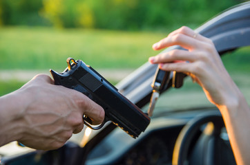 thief used a gun threatened woman driver at car on street, pick up keys to steal