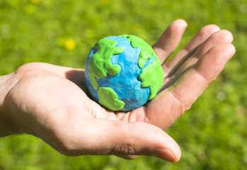 Plasticine Earth in man`s hand on the natural background.