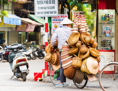 Fototapeta HANOI, VIETNAM - DECEMBER 16, 2016: The seller of wicker baskets in the local market. Copy space for text.
