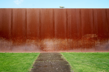 Road blocked by a copper wall leading to nowhere. Graffiti on the wall.