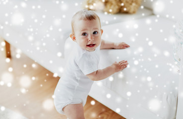 childhood, babyhood, emotions and people concept - happy little baby boy or girl at home over snow