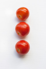 Three red  tomatoes on a white .