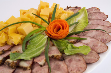 decoration of a plate with meat cut. Cheese, homemade sausage, bacon with greens