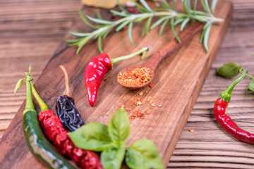 Chilli powder and fresh and dried peppers on table background