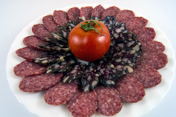 Sliced ​​sausage of two flowers and a tomato on a light background