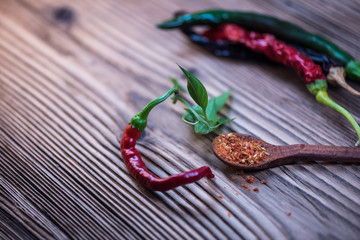 Chilli powder and fresh and dried peppers on table background