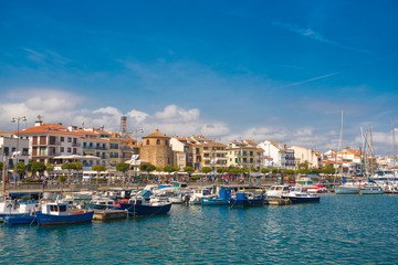 Fototapeta na wymiar CAMBRILS, SPAIN - APRIL 30, 2017: View of port and city waterfront with Church Of Saint Peter in middle and Torre del Port. Copy space for text.
