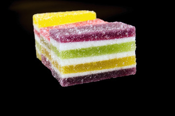 pieces of marmalade with colorful stripes on a dark background
