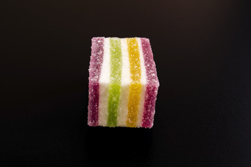 tasty, sweet piece of colorful marmalade on a black background