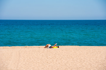 Fototapeta na wymiar MIAMI PLATJA, SPAIN - APRIL 24, 2017: The man on the beach sunning. Copy space for text.
