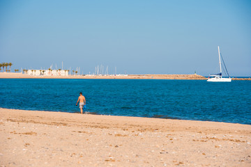 MIAMI PLATJA, SPAIN - APRIL 24, 2017: A man walks along the sandy beach in the distance. Copy space...