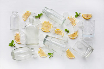 Glasses and bottle for drinks with lemon slices, mint and ice on