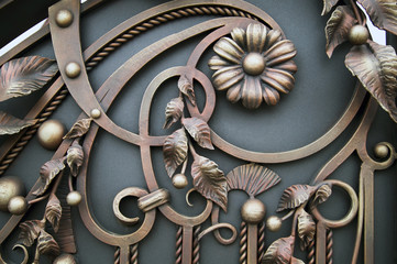 Part of the gate with forged elements and a decorative flower made of metal